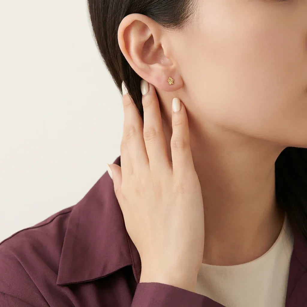 أقراط عيار 18 مزخرفة بتصميم زهرة من غامية، تظهر تفاصيل دقيقة وجميلة في الصورة.